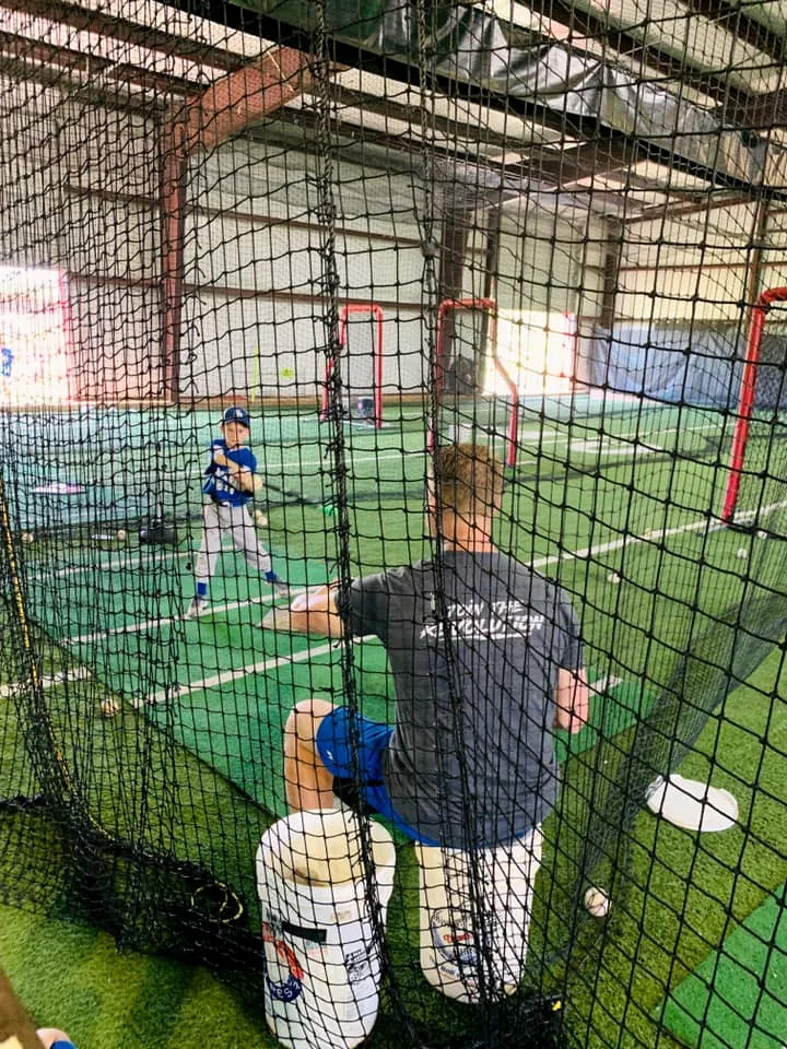 A player taking swings in the indoor batting lane