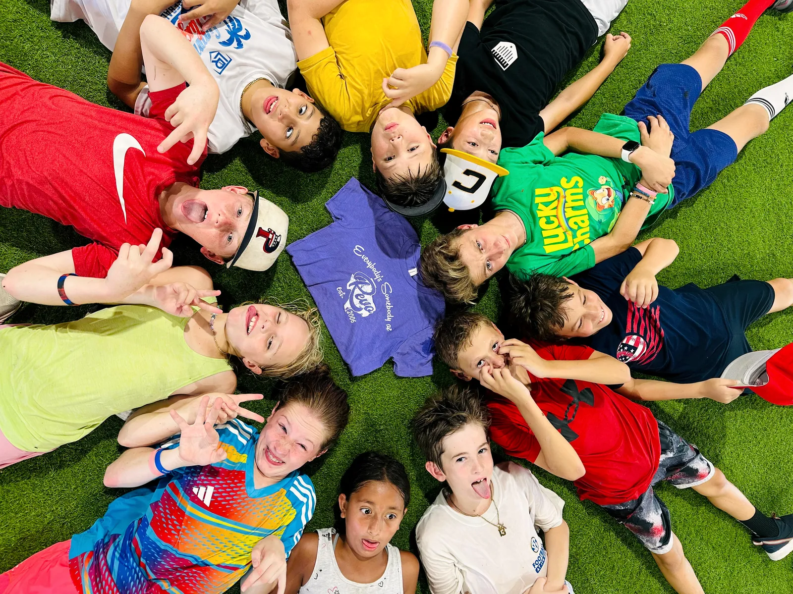 Campers lying in a circle on the turf looking up at the camera