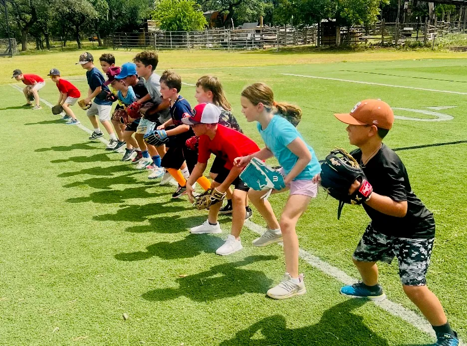 A long line of campers in ready position across the turf field at Revo Sports camp