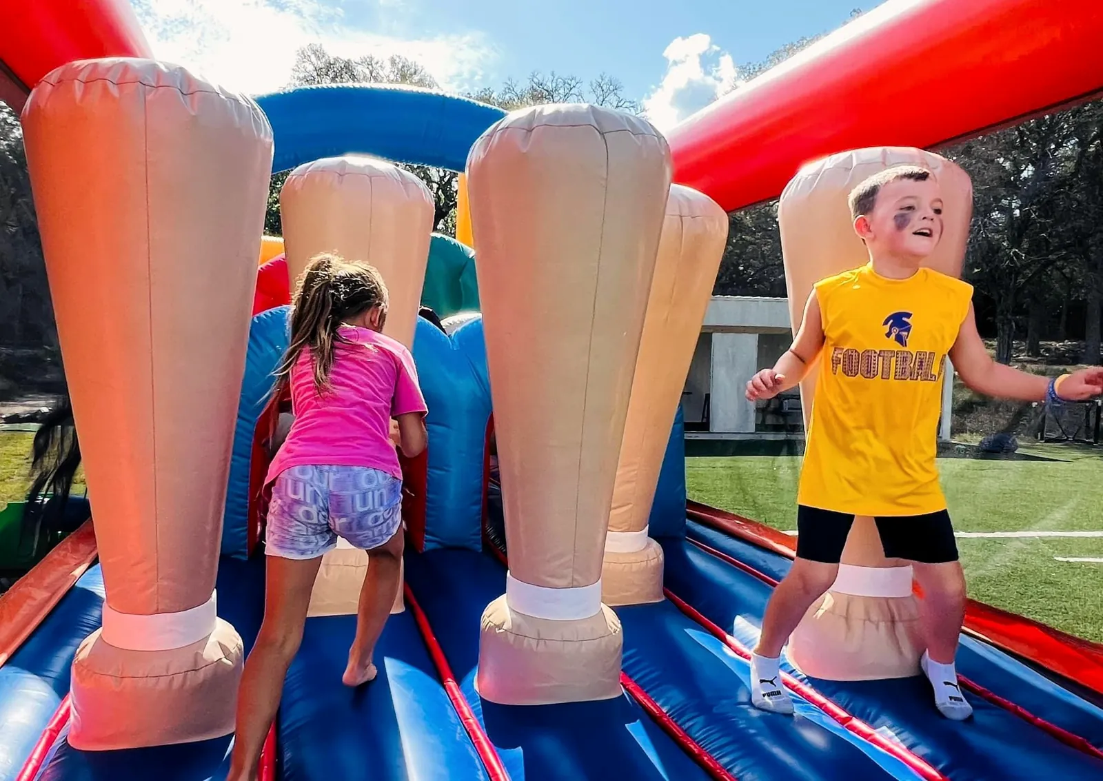 Children racing through an inflatable obstacle course at MOMsanity day camp