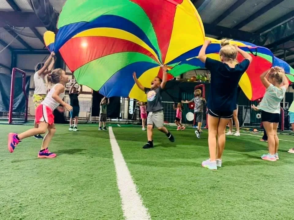 Campers playing a parachute game indoors