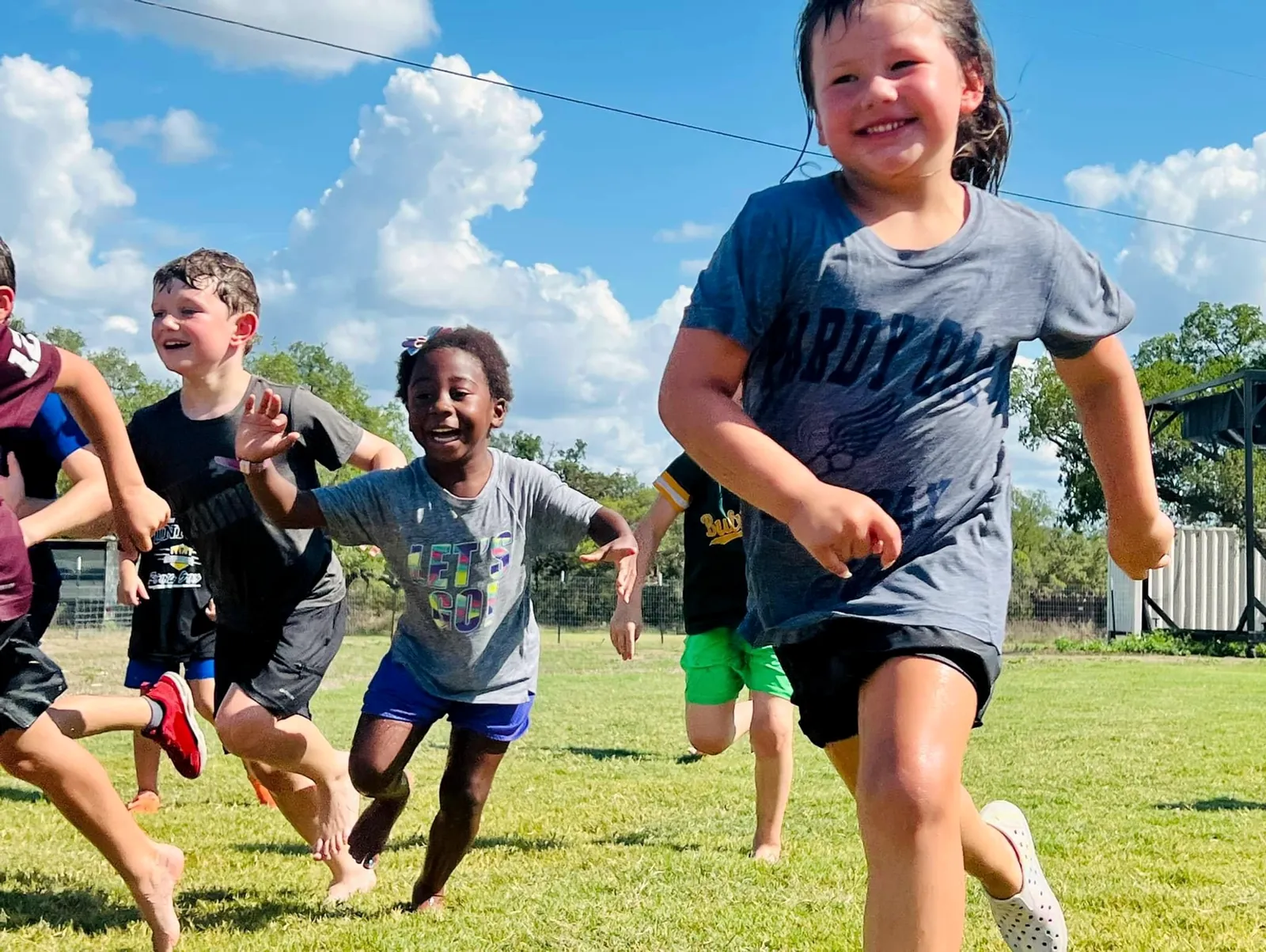 A group of campers sprinting across the grass field during a Revo Sports multi sport camp