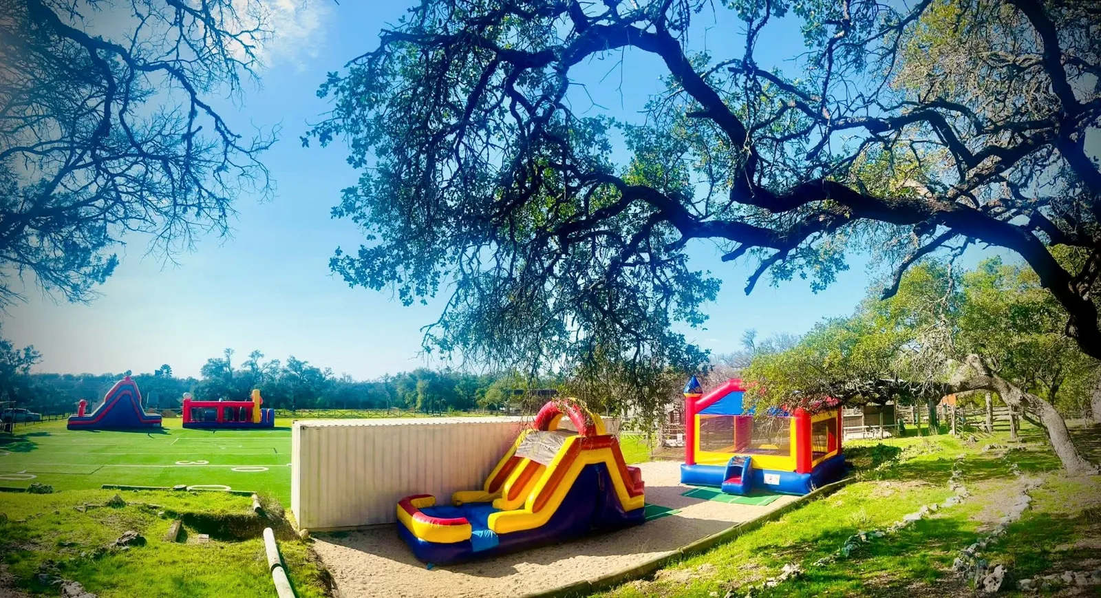 The open field at Revo Sports on the Hill with inflatable slides set up under mature live oak trees