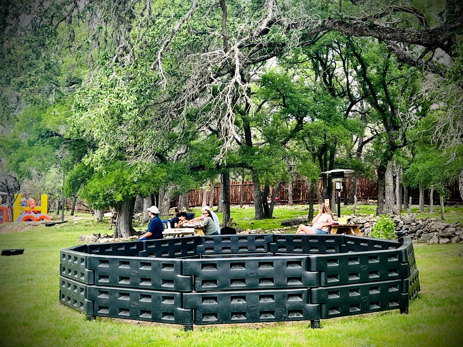 Picnic tables and a gaga ball pit under the oak grove at Revo Sports