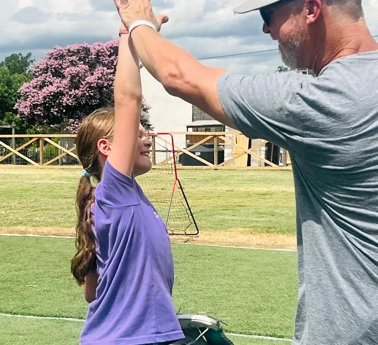 A Revo Sports coach high fiving a young player after a good swing
